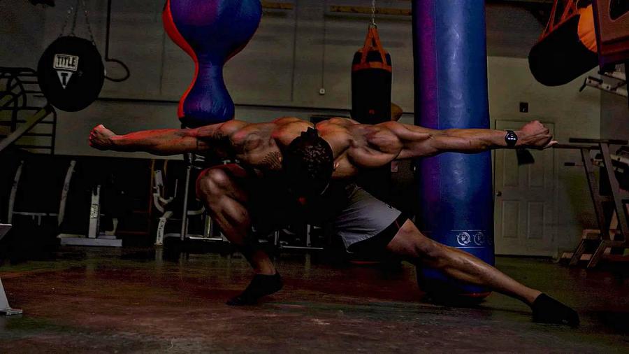 Eric Shelton holding a posing stretch in the gym